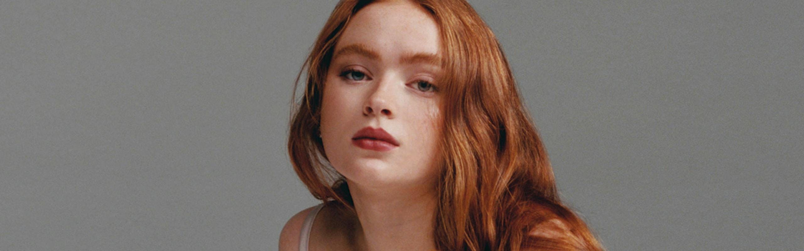 Sadie Sink red hair cream dress gray and white backdrop