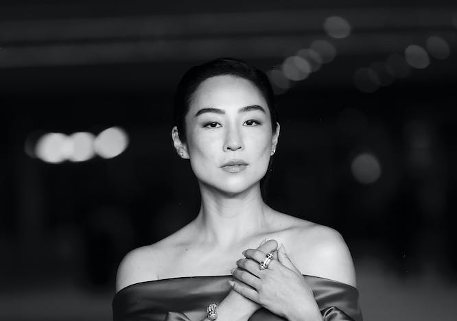 Black and white image of Greta Lee in a dress with puffy sleeves