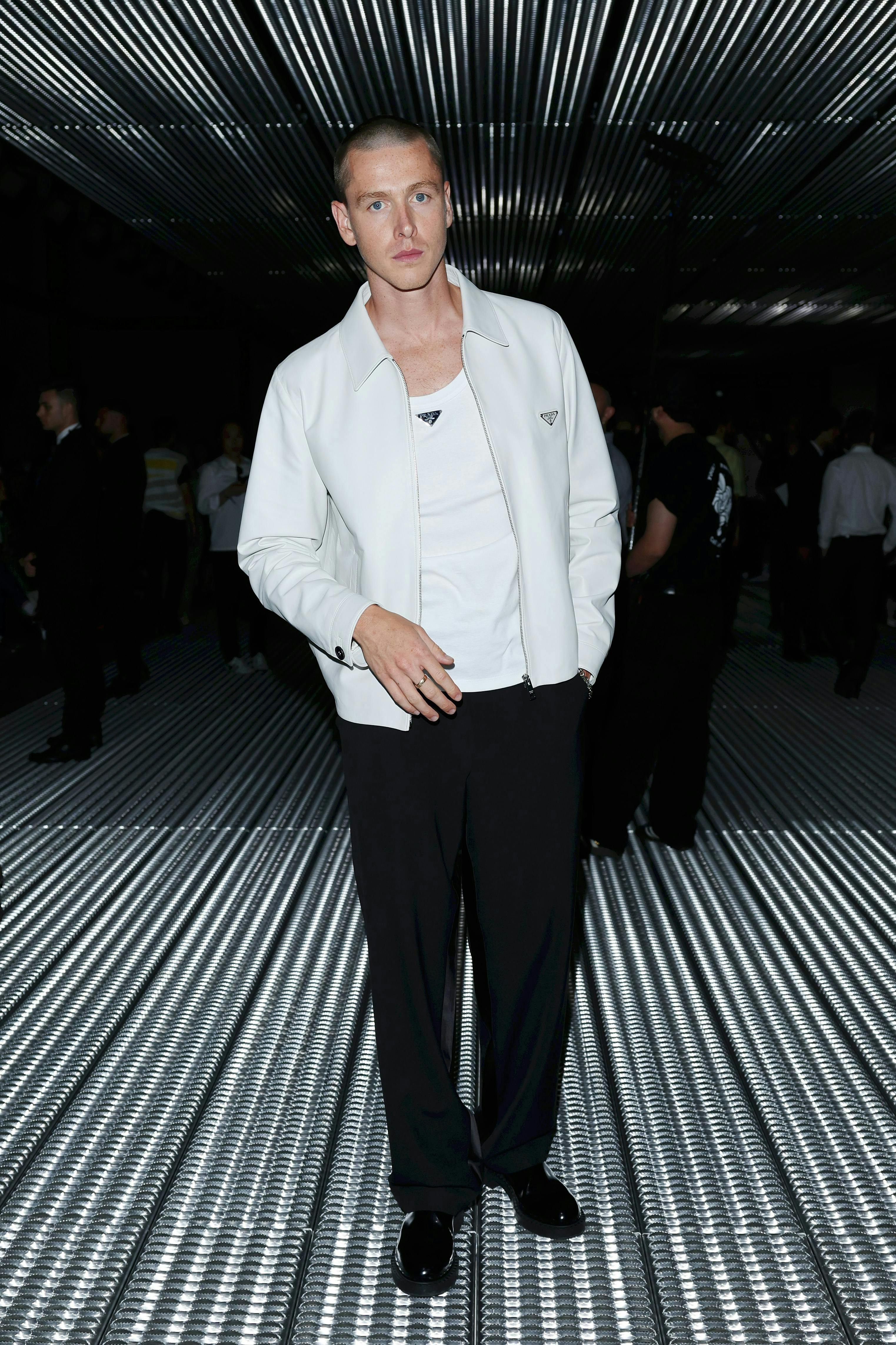 harris dickinson in a white prada jacket, white prada shirt, and black pants