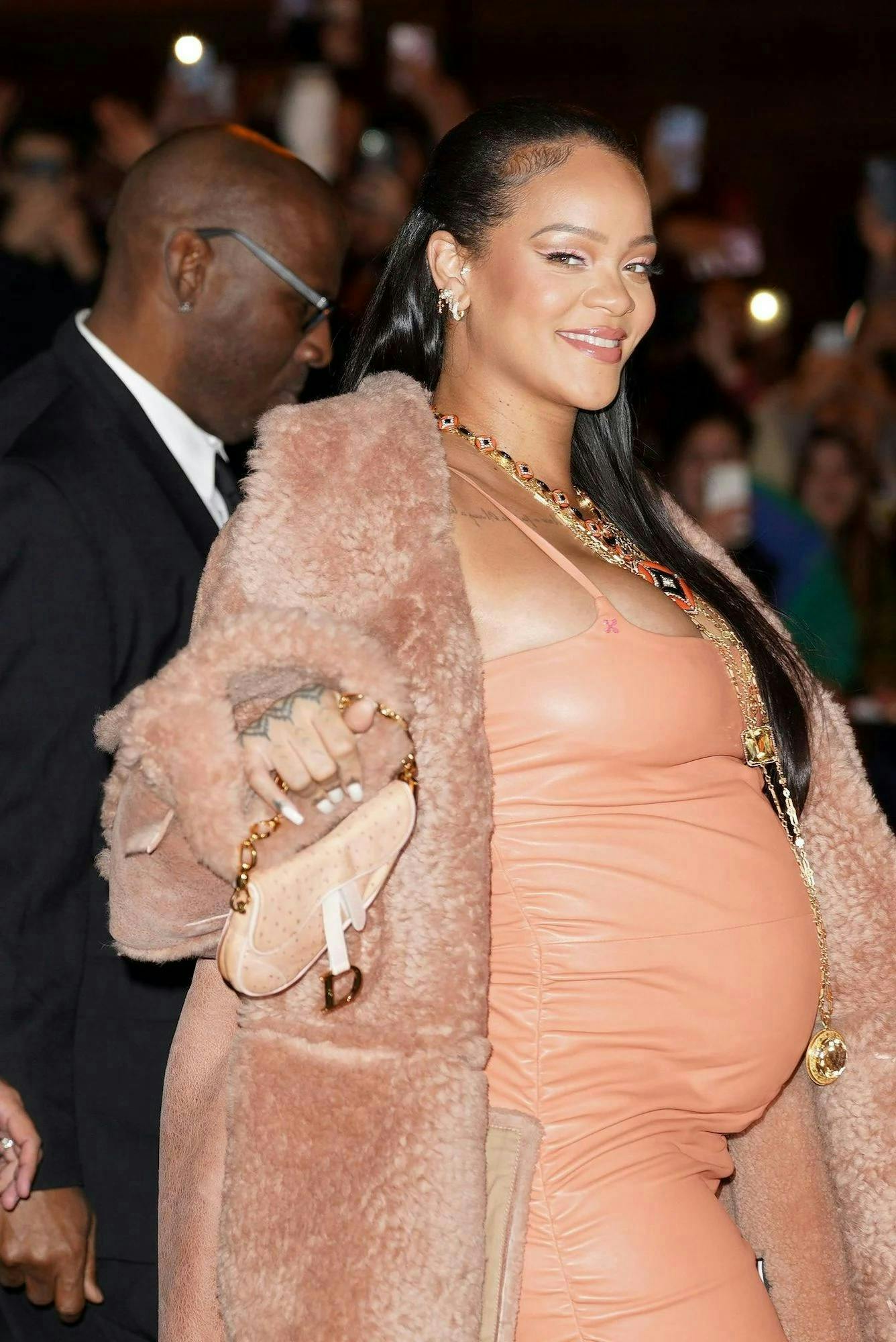 Rihanna in a salmon pink dress and fur coat best maternity outfits