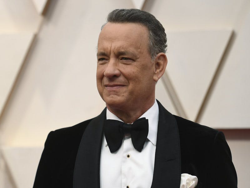 Tom Hanks in a black suit and bowtie, with a white shirt underneath. 
