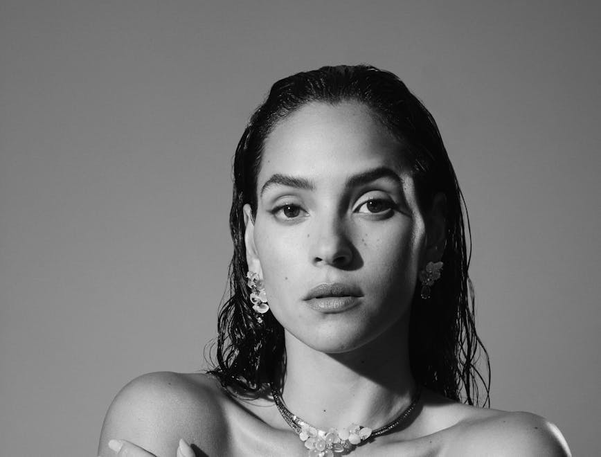 black and white image of adria arjona wearing a white tube top and statement necklace