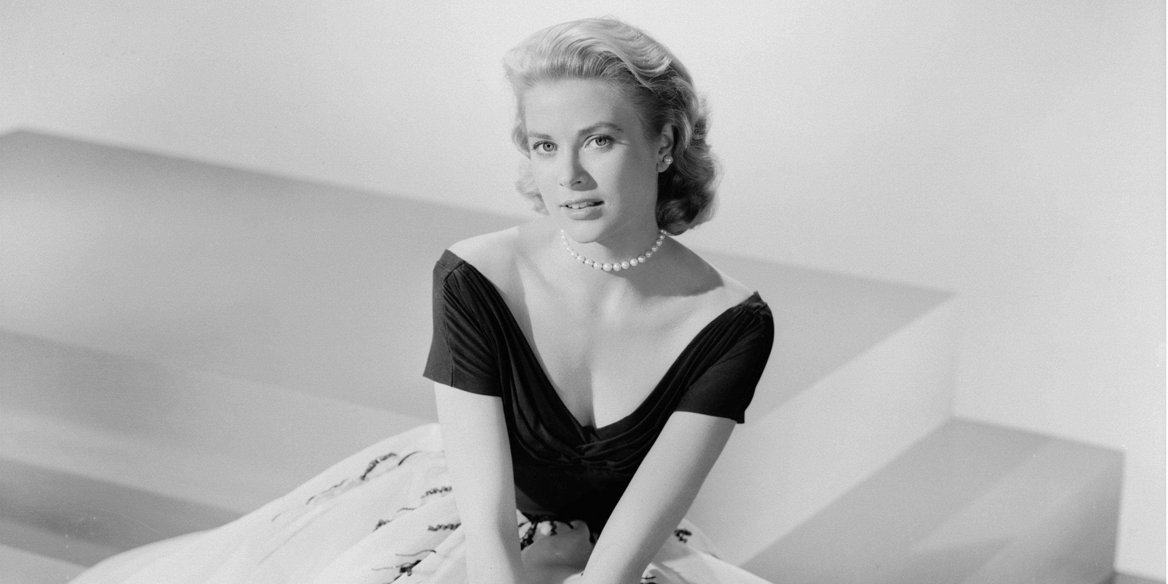 young grace kelly posing for a portrait wearing a black top and pearl necklace