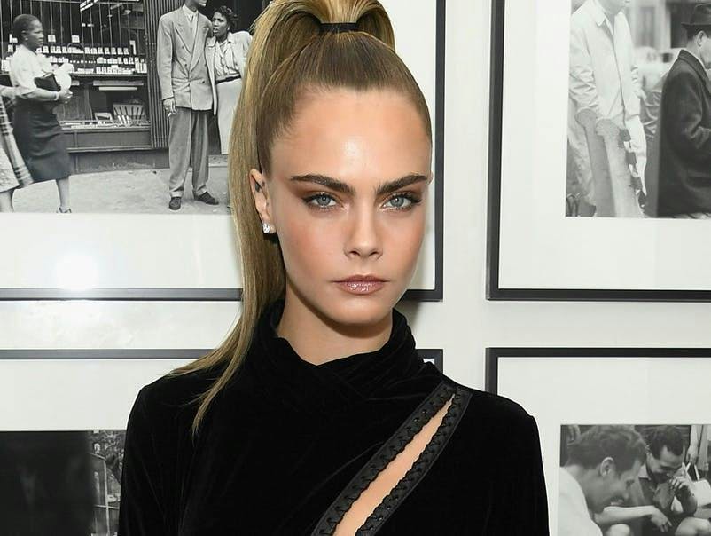 Close up of Cara Delevigne with a slicked back pony tail
