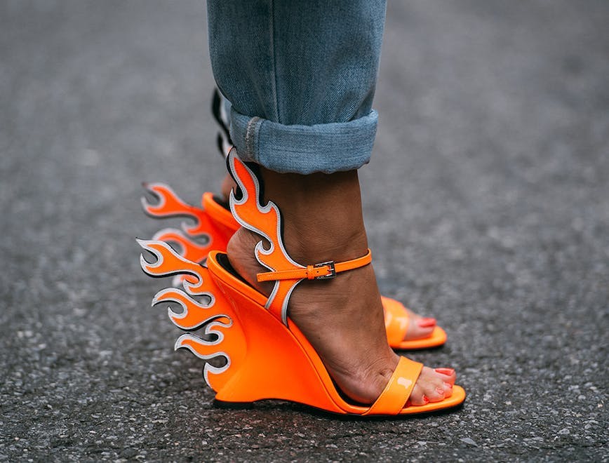 Closeup of someone's feet wearing the neon orange Prada wedges with flames. 