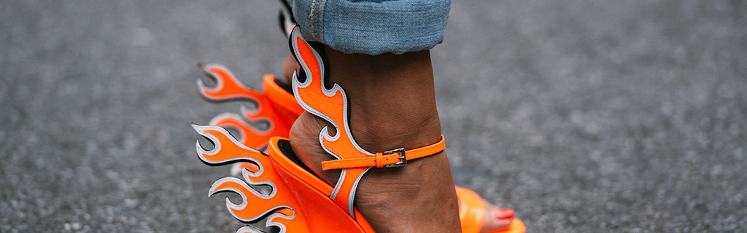 Closeup of someone's feet wearing the neon orange Prada wedges with flames. 