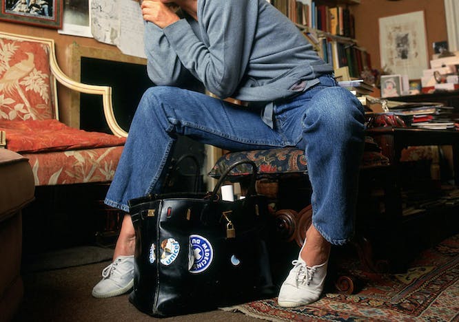 jane birkin sitting on a chair beside the hermes bag named after her