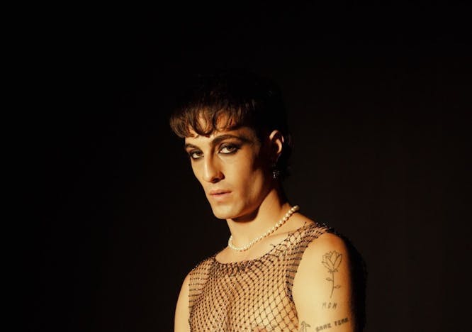 Man wearing a fishnet top and heavy undereye liner