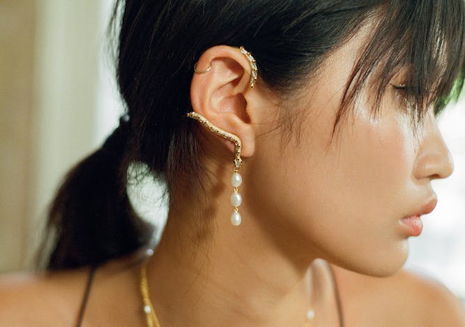 model wearing gold ear cuff with pearl drop detail