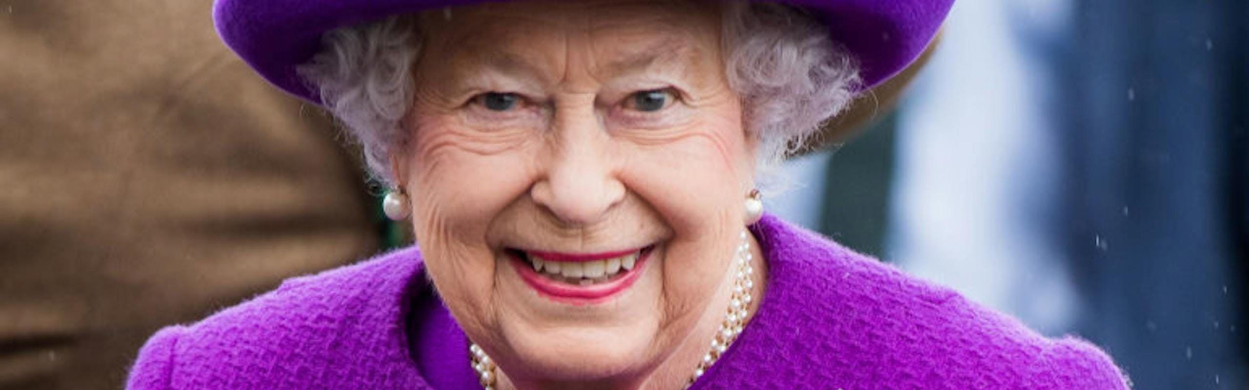 Queen Elizabeth wearing a purple suit and hat