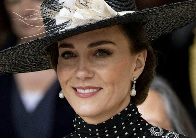 Kate Middleton in a black wide-brimmed hat with a large white flower