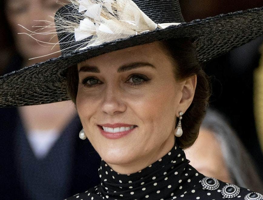 Kate Middleton in a black wide-brimmed hat with a large white flower