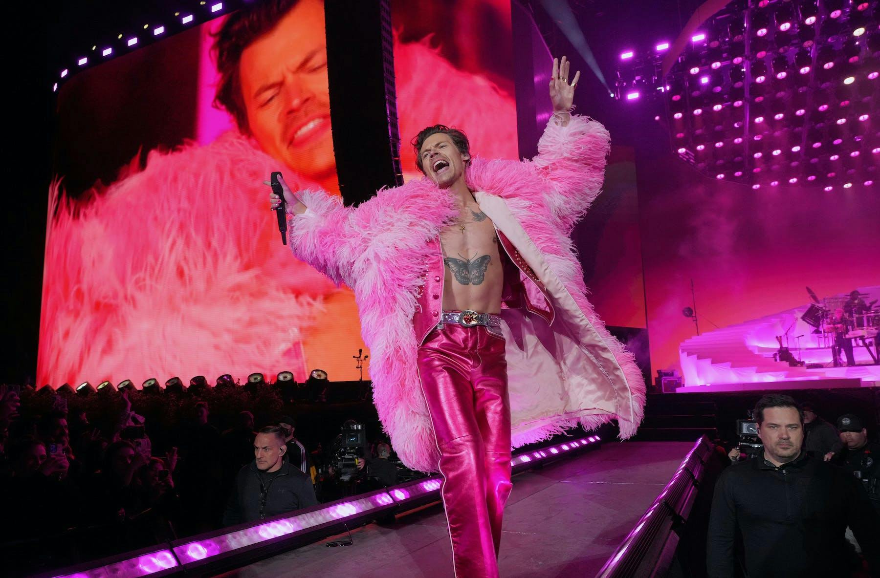 Harry Styles in a pink fur coat and matching pink pants.