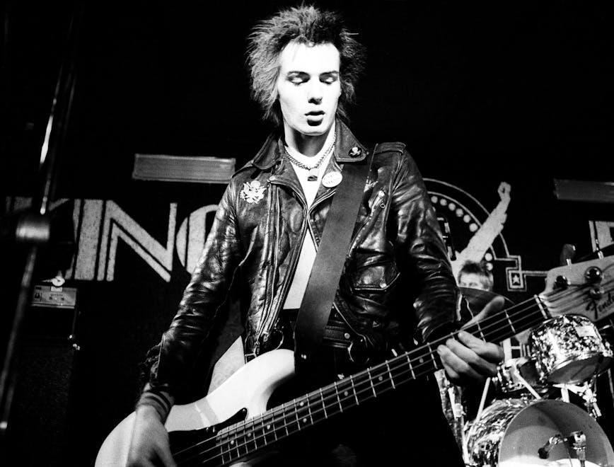 Sid Vicious playing guitar on stage.