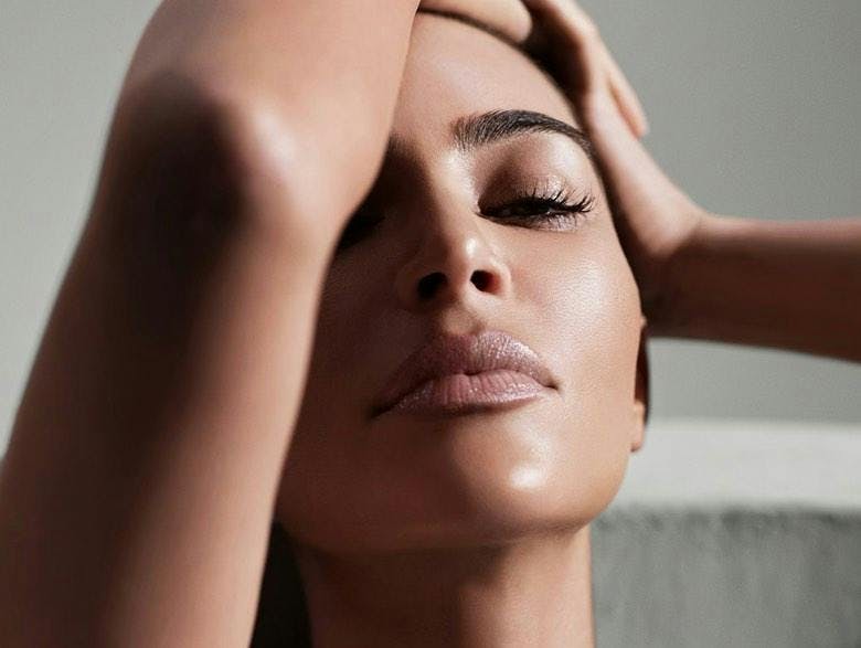 Kim Kardashian posing with her arm in front of her face