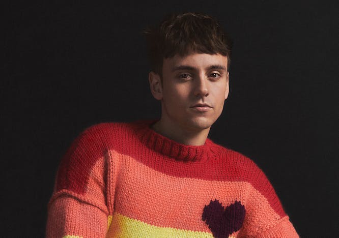 Athlete Tom Daley wearing a rainbow striped sweater.