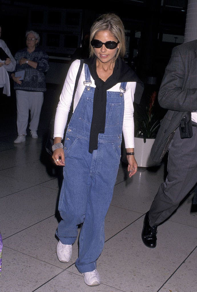 Sarah Michelle Gellar in blue overalls, a white long sleeve under shirt, and black sunglasses