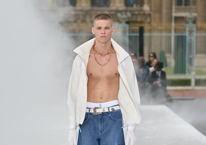 Model for Givenchy in a white jacket and baggy denim.