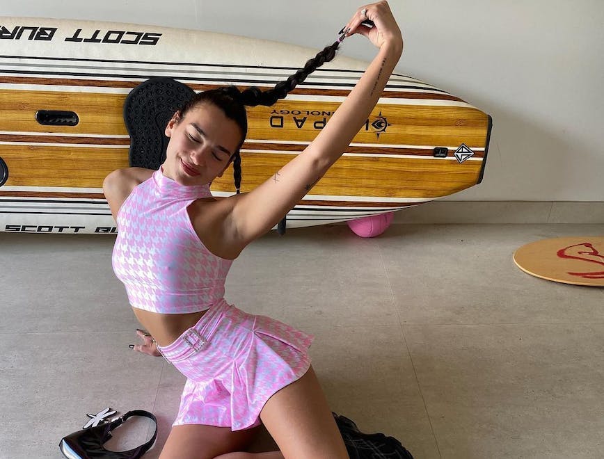 Dua Lipa, the queen of preppy summer trends, poses in a matching pink houndstooth skirt and crop top.
