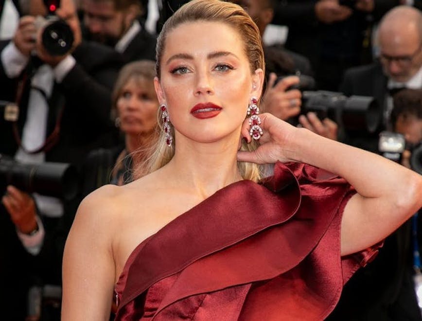 Actress Amber Heard on the red carpet in a red dress.