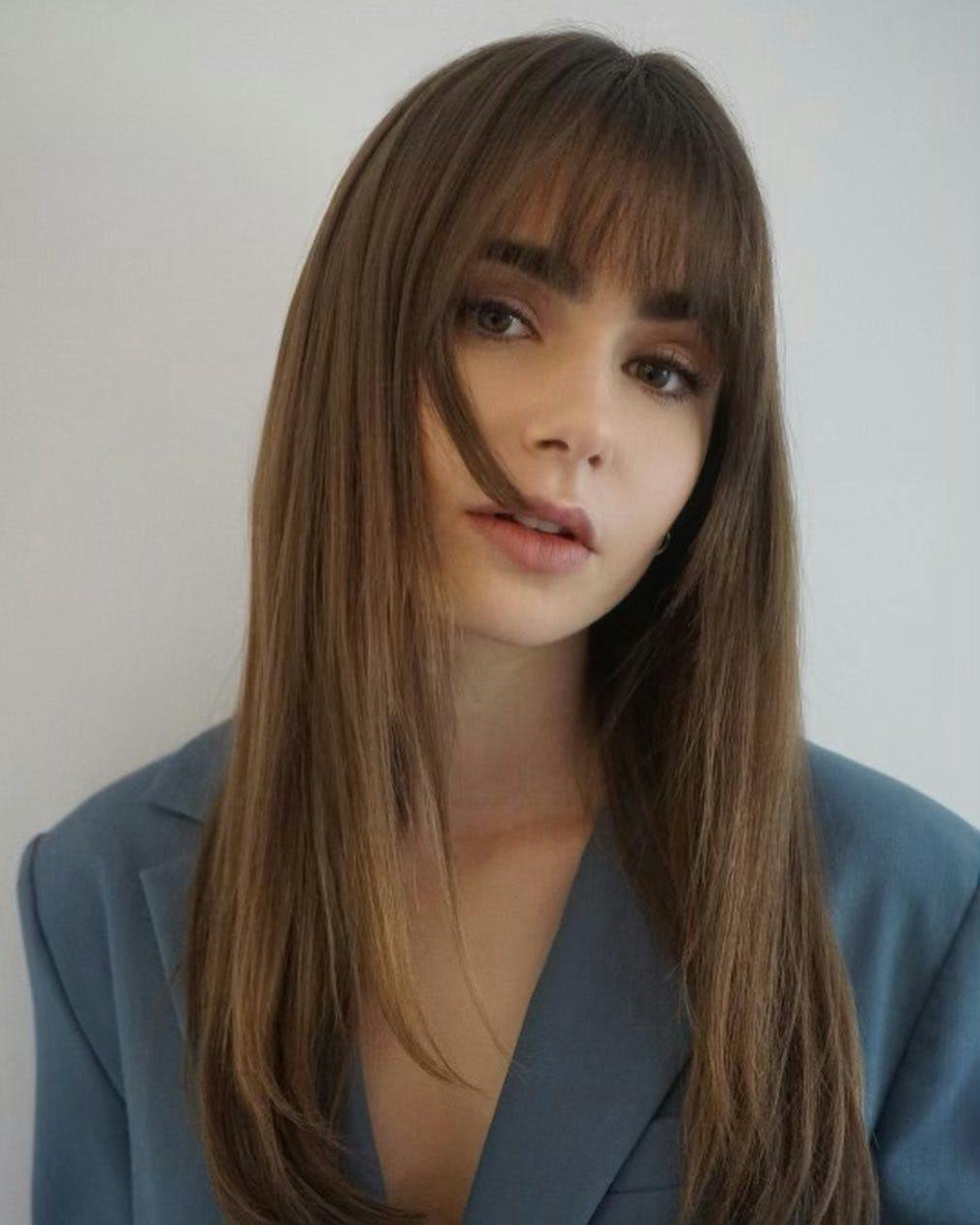 Lily Collins in a blue suit jacket and styled, straight hair.