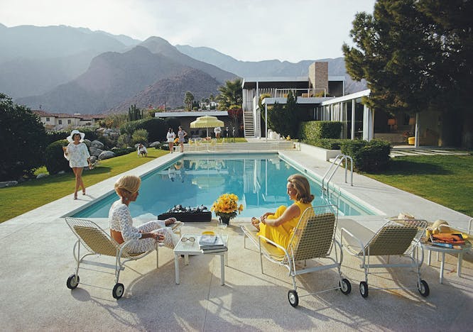 slim aarons photo of two women sitting beside a pool in palm springs