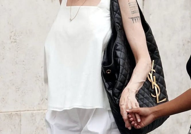 angelina jolie in all white carrying a black saint laurent bag
