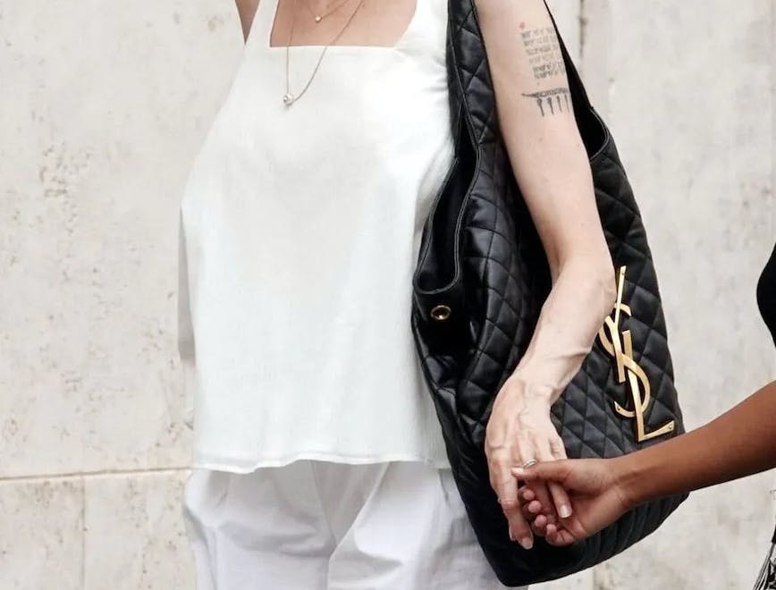angelina jolie in all white carrying a black saint laurent bag