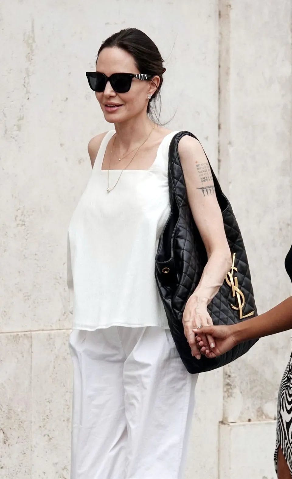 angelina jolie in all white carrying a black saint lauren tbag