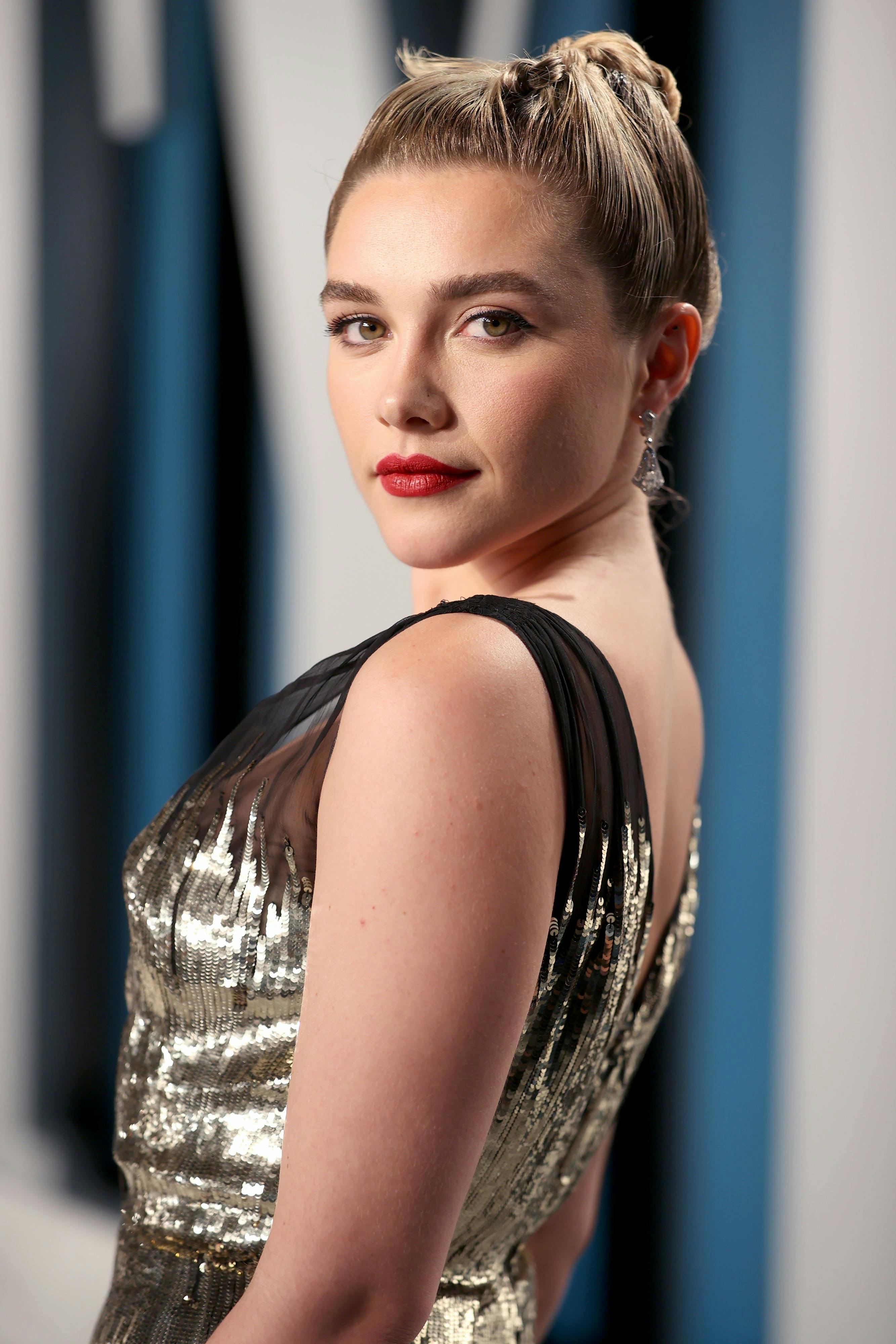 Florence pugh in a gold sequined gown with black detailing on the red carpet