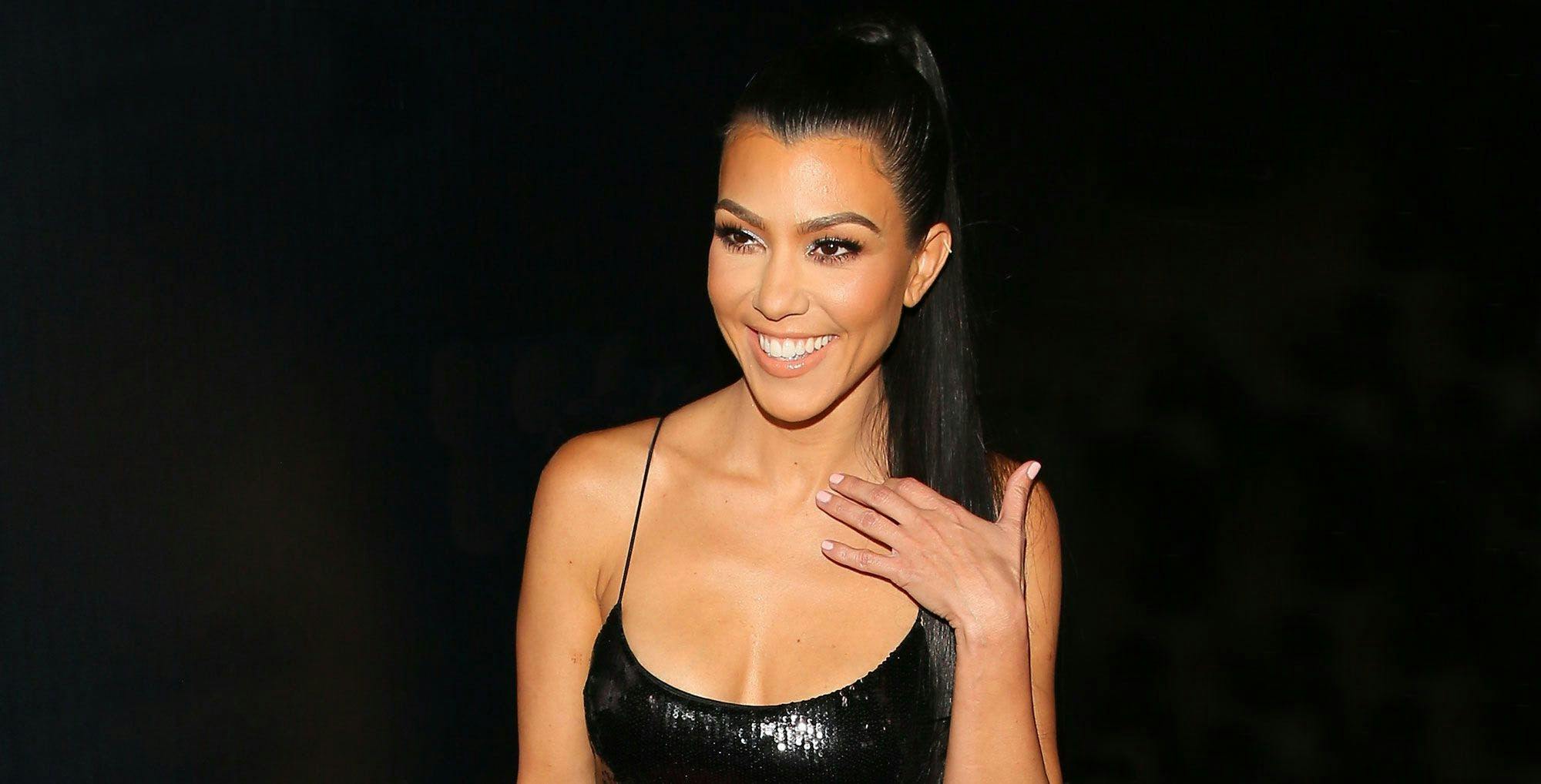 Kourtney Kardashian wearing a black dress and smiling