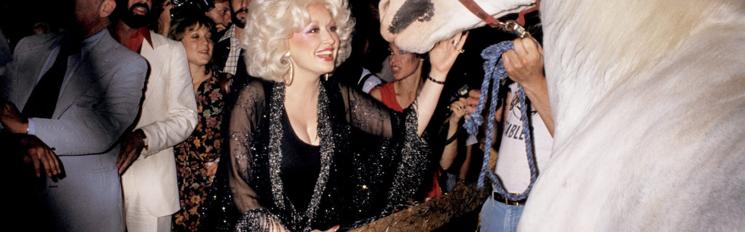 Dolly Parton petting a horse while partying at Studio 54.