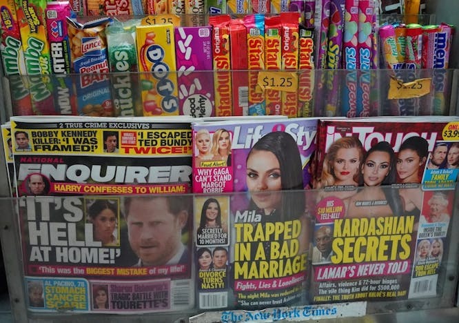 Tabloid magazines on a news stand including headlines about Meghan Markle and the Kardashians.