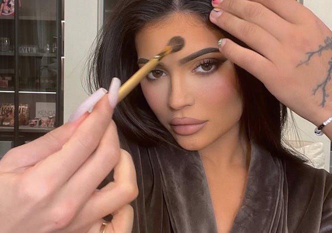 Kylie Jenner poses for a photo while makeup artists work on her face.
