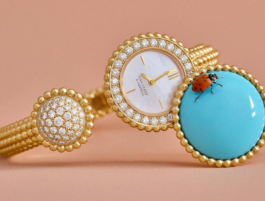 van cleef watch with gold beading and a turquoise watch face cover