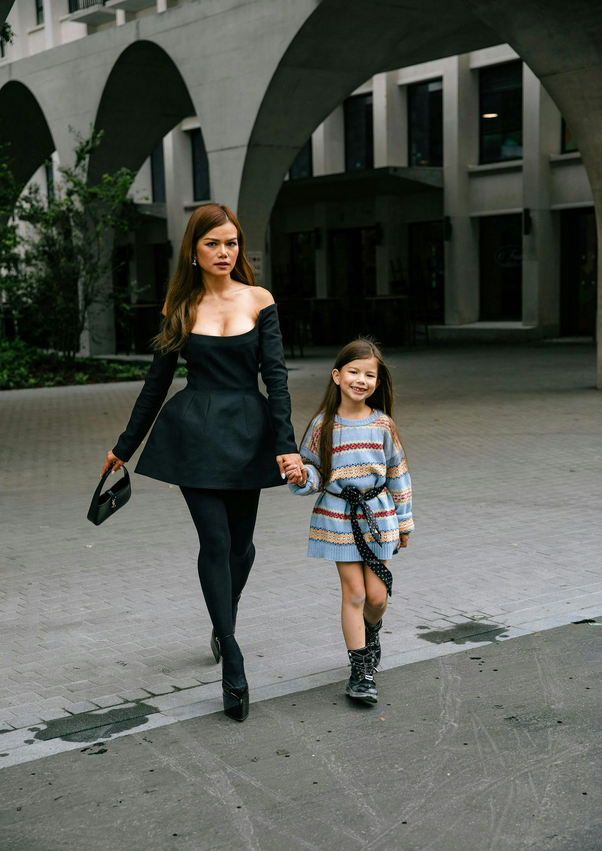 Woman in black dress walking with child