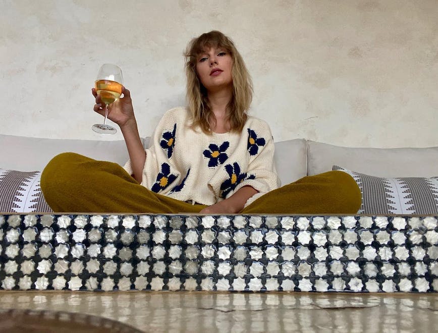 taylor swift wearing a sweater with blue flowers and drinking wine