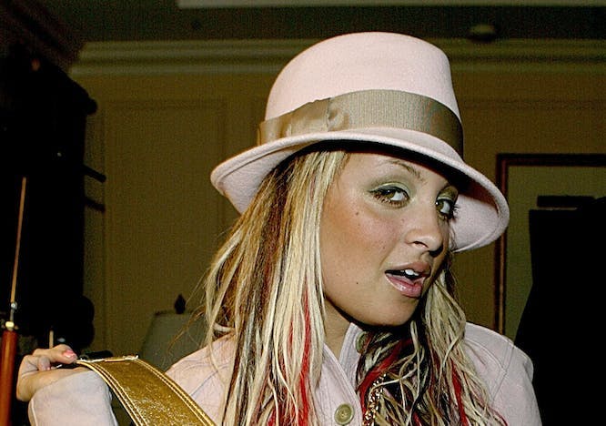 Nicole Richie in a pink hat and jacket on a black background