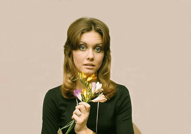 Olivia Newton-John with flowers tan background brown table