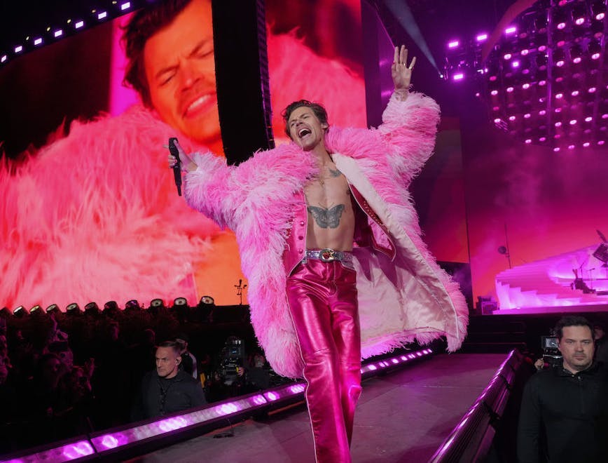Harry Styles in a pink feather coat, vest, pants.