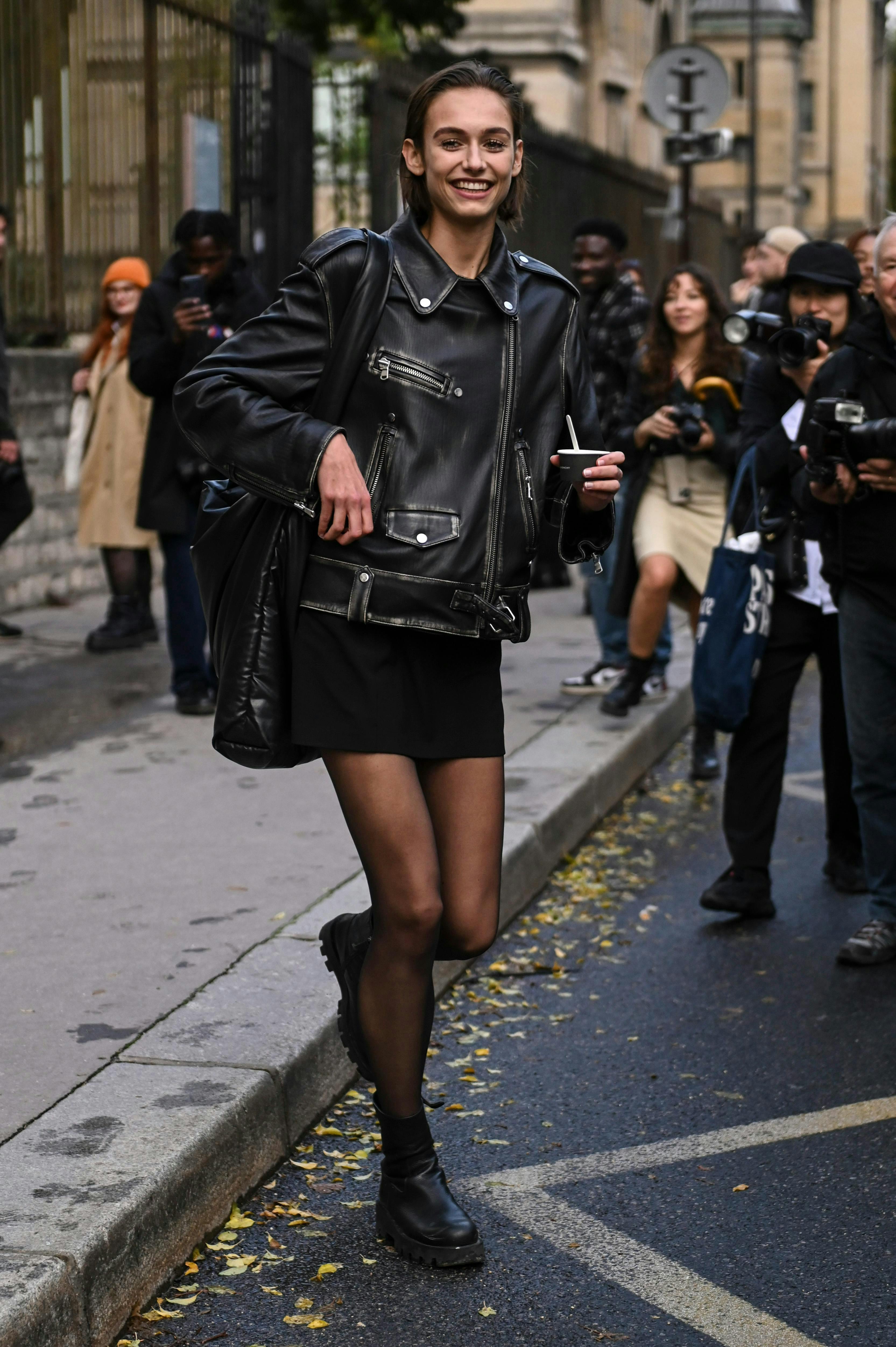 model on street wearing black miniskirt and leather jacket.