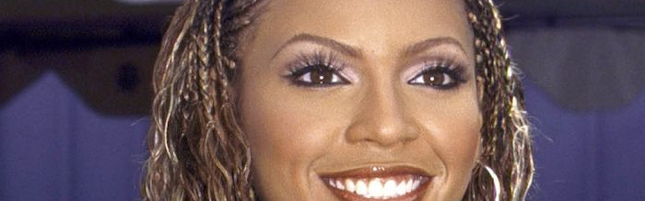 Beyonce in braids and smiling with brown lip liner and clear gloss.