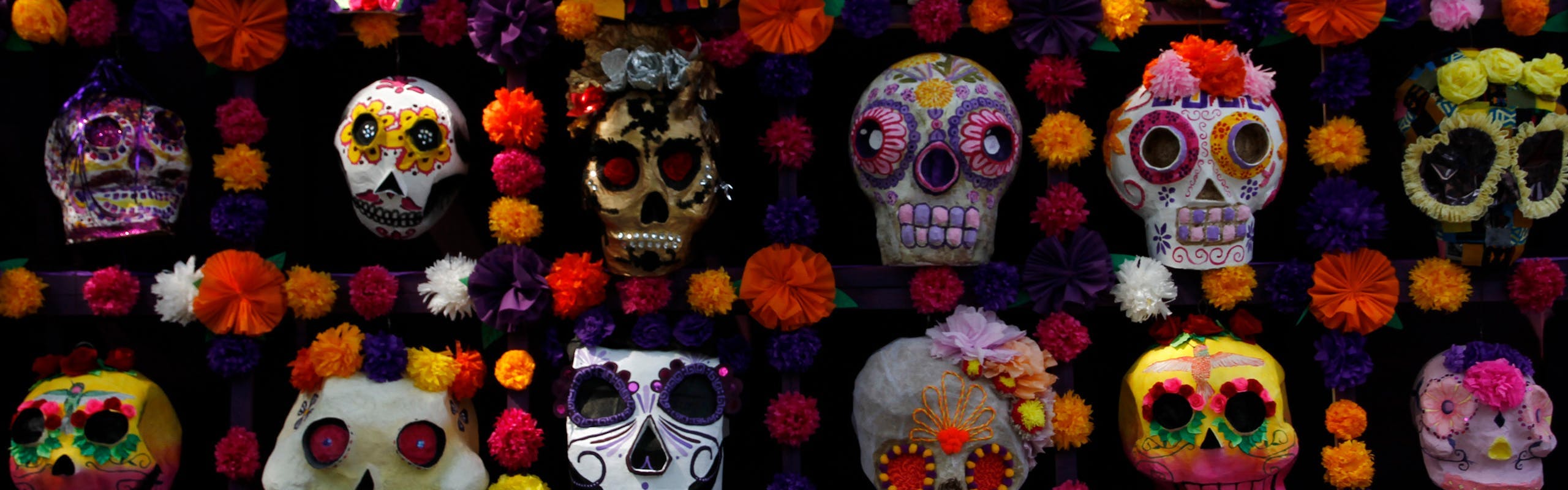 Sugar Skulls attached on a wall with flowers.