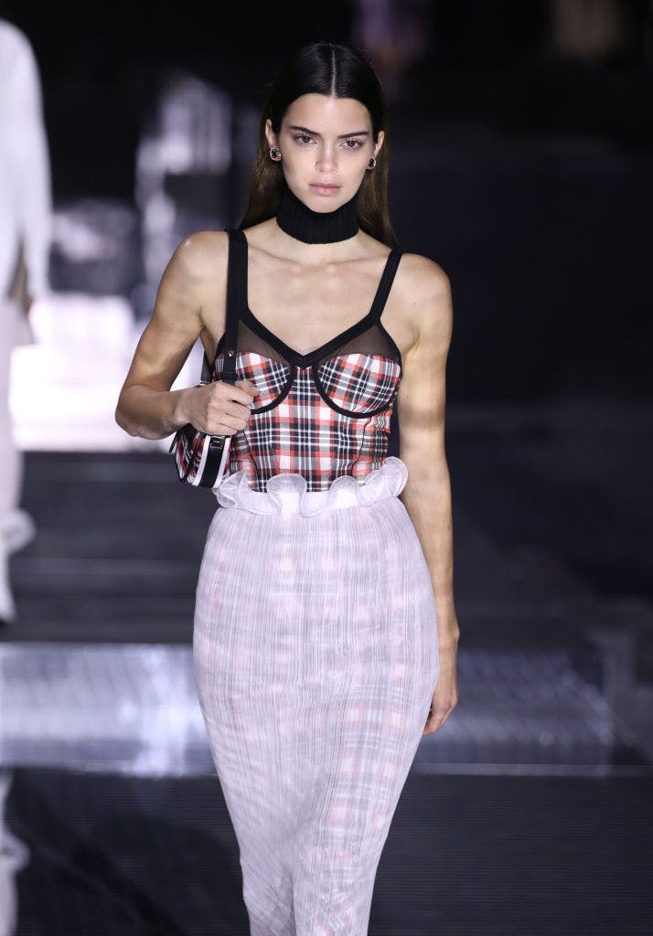 A woman in a plaid top and white skirt.
