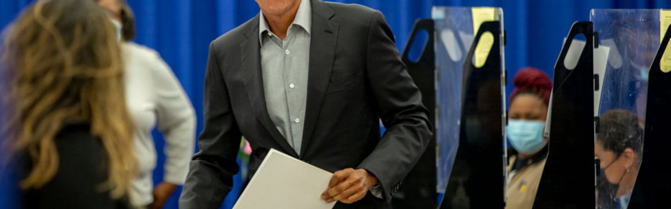 A man in a black suit holding a paper.