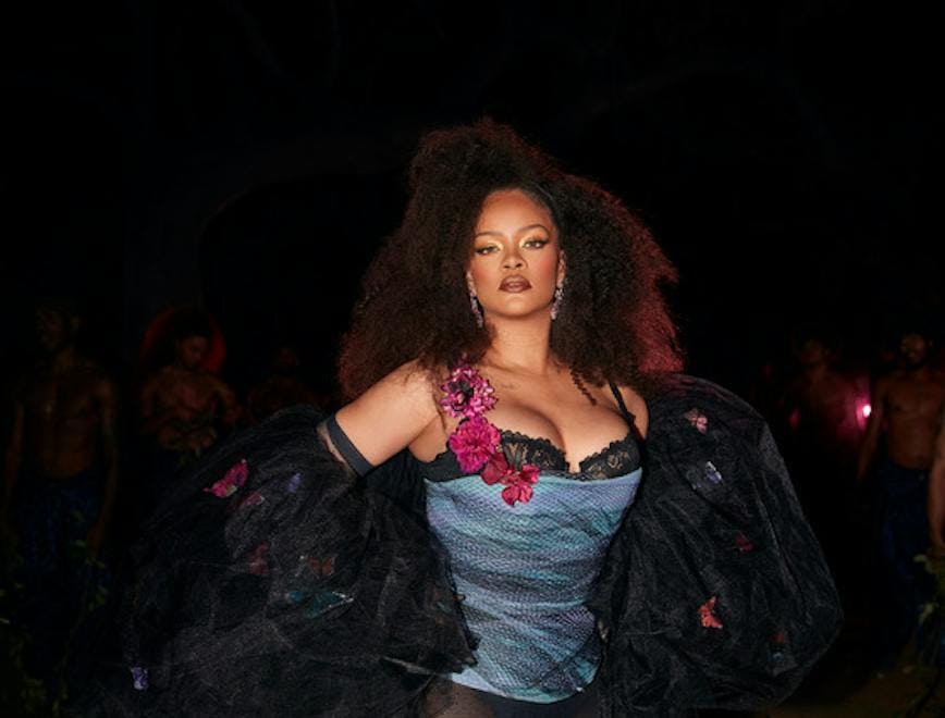 A woman dressed in a blue corset, black stockings, and tulle shrug.