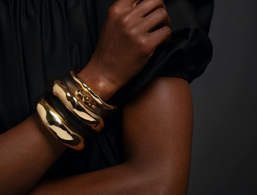 woman wearing a black shirt and three melted gold bracelets