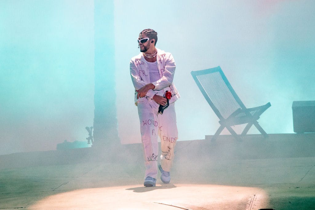 bad bunny on stage wearing all white and sunglasses