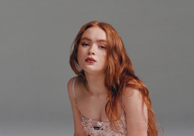 Sadie Sink red hair cream dress gray and white backdrop