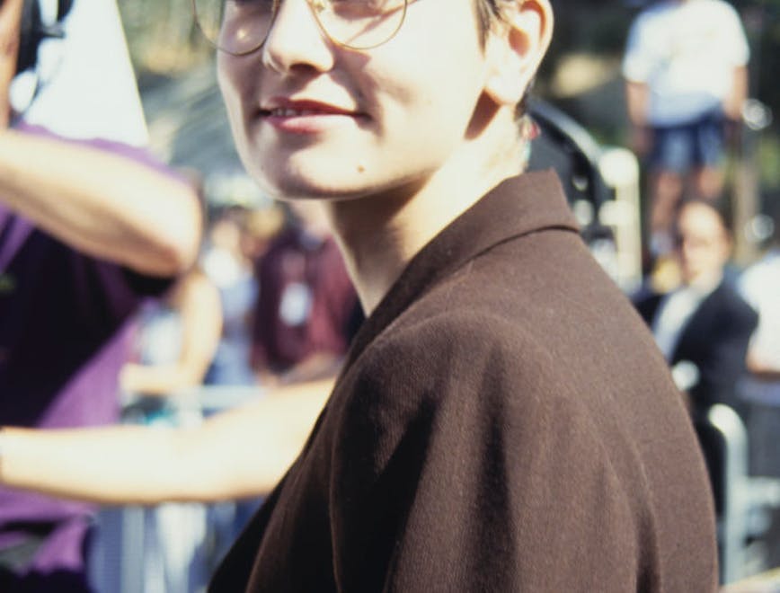 A woman in glasses and a brown jacket looking at the camera.